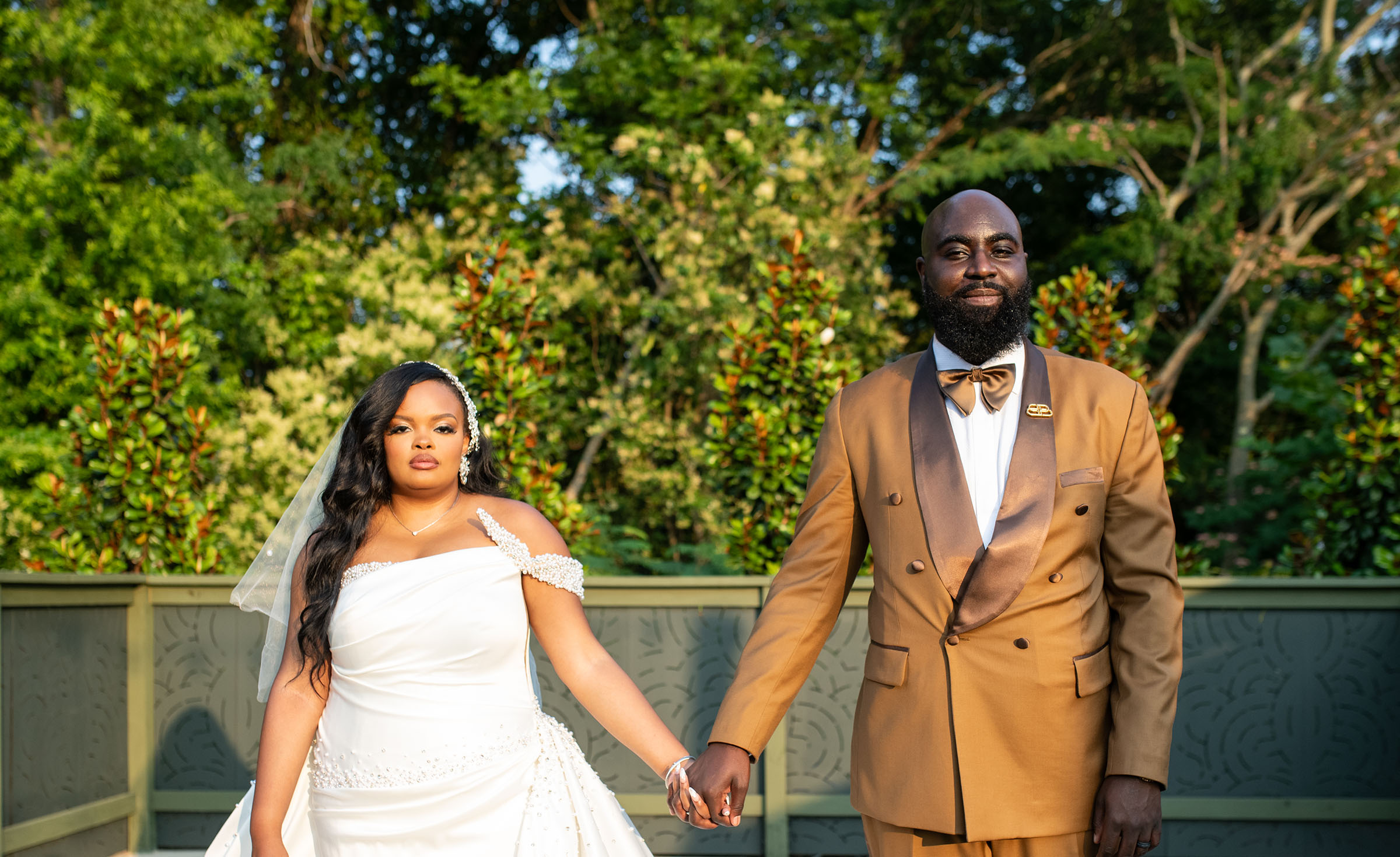 Bride and groom holding hands, looking into the camera.