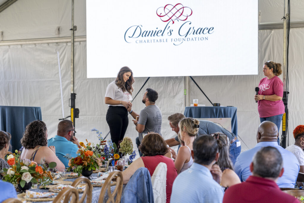 Woman being proposed to in front of people at a Daniel's Grace fundraiser for cancer.